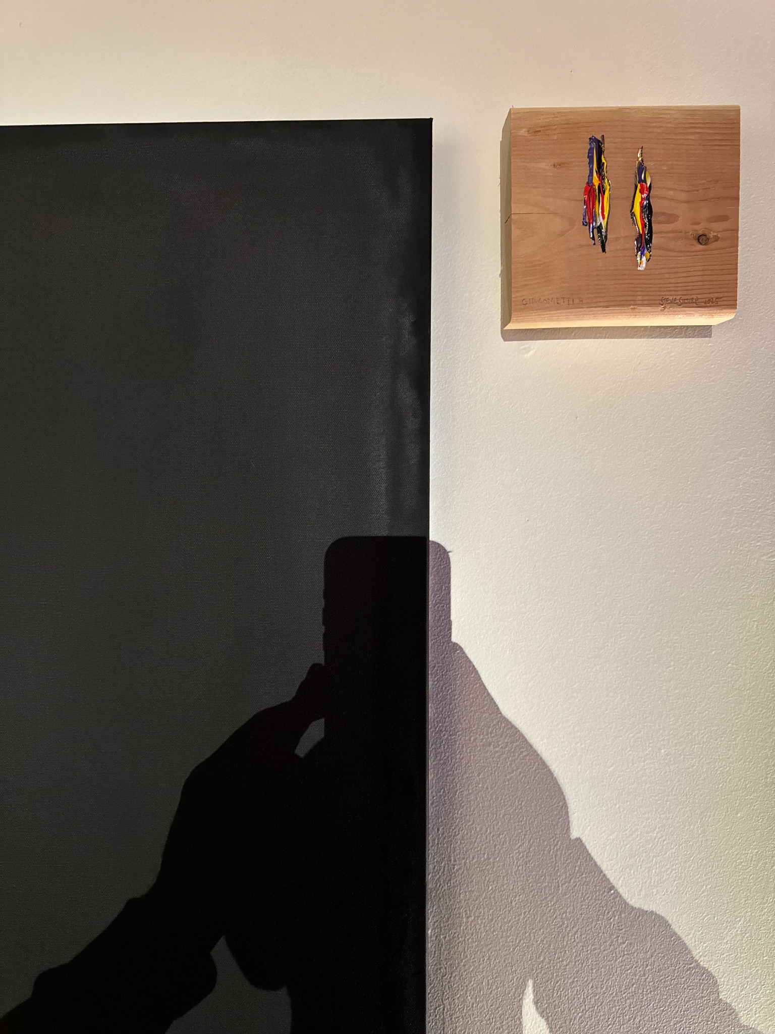 Small artwork on wood beside a black canvas